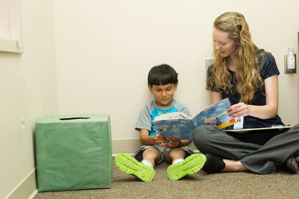 Student helping child read a book